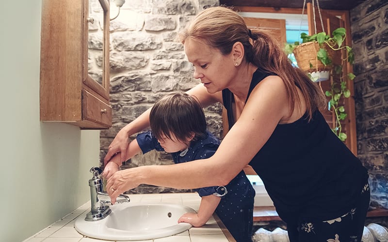 mom helping boy wash hands in bathroom