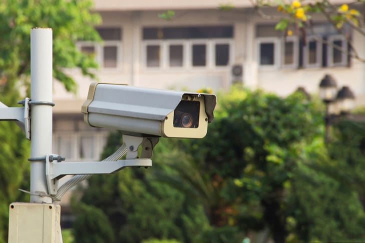 outdoor security camera with house and trees behind