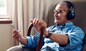 man in seat listening to music and holding a cane