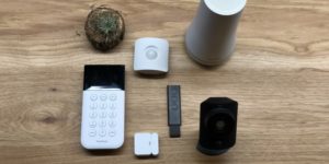 SimpliSafe keypad, entry sensor, motion sensor, key fob, base station, and simplicam on wooden surface