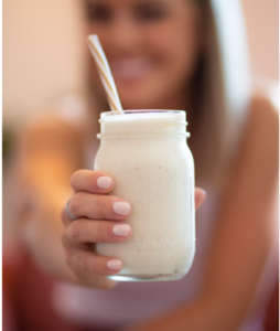 Banana Smoothie held by smiling woman. Photo by Amanda Vicks on Unsplash