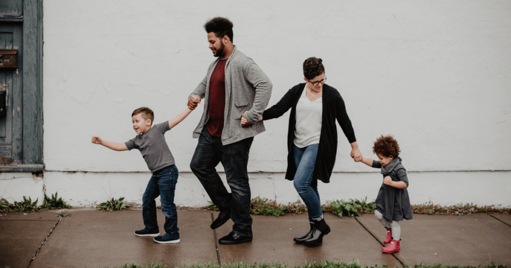 Parents and children walking down a sidewalk